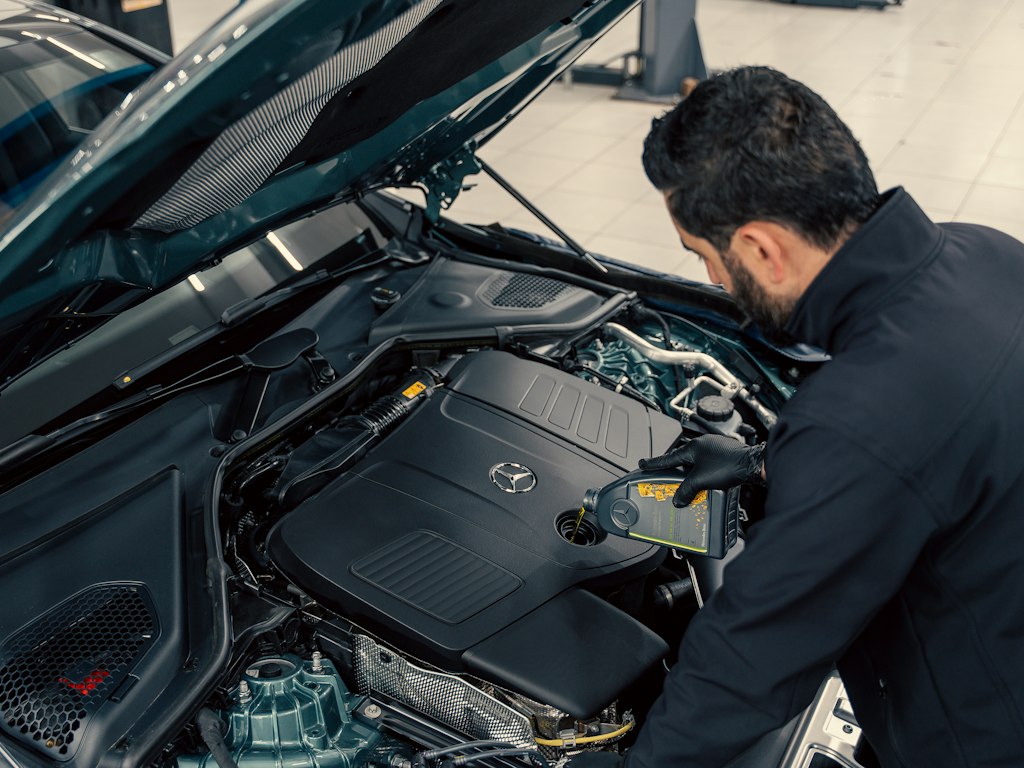 Mechanic working under the hood of a car in a repair shop