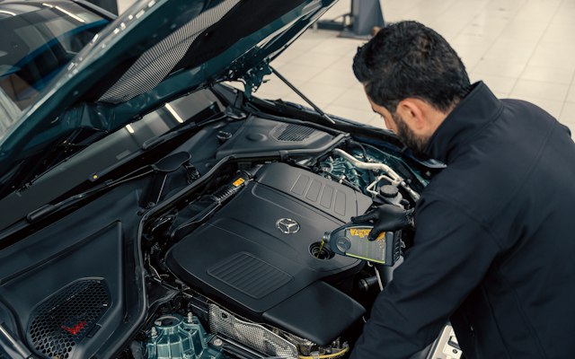 Mechanic working under the hood of a car in a repair shop